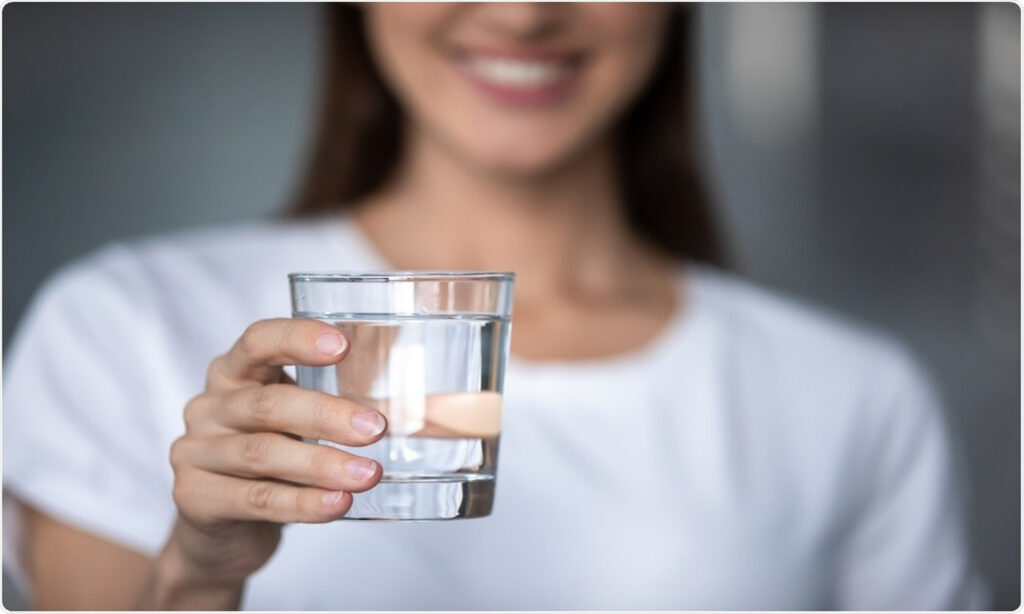 lady holding a warm glass of water which is good for health